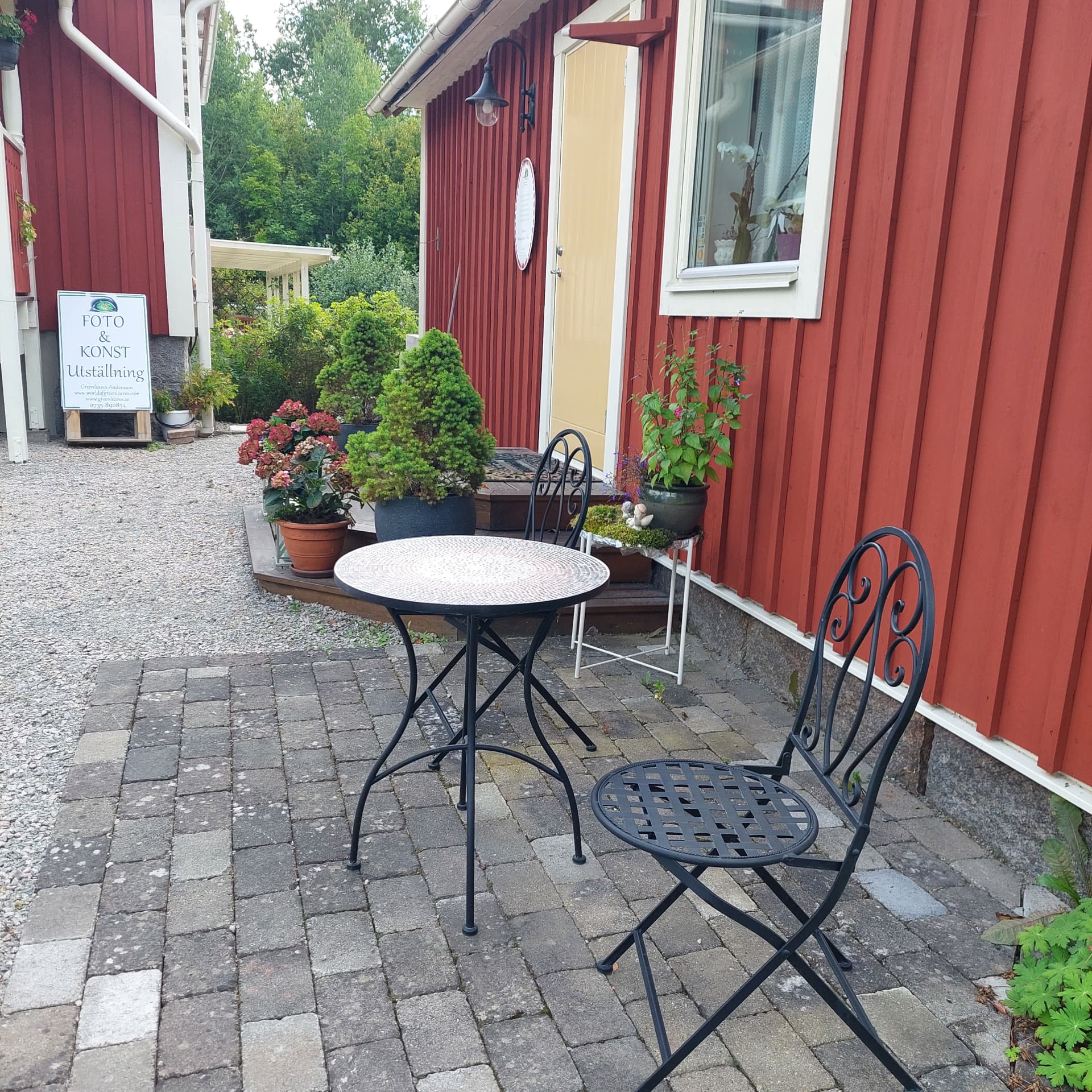Uteplatsen vid det röda huset med skylten Foto & Konst utställning